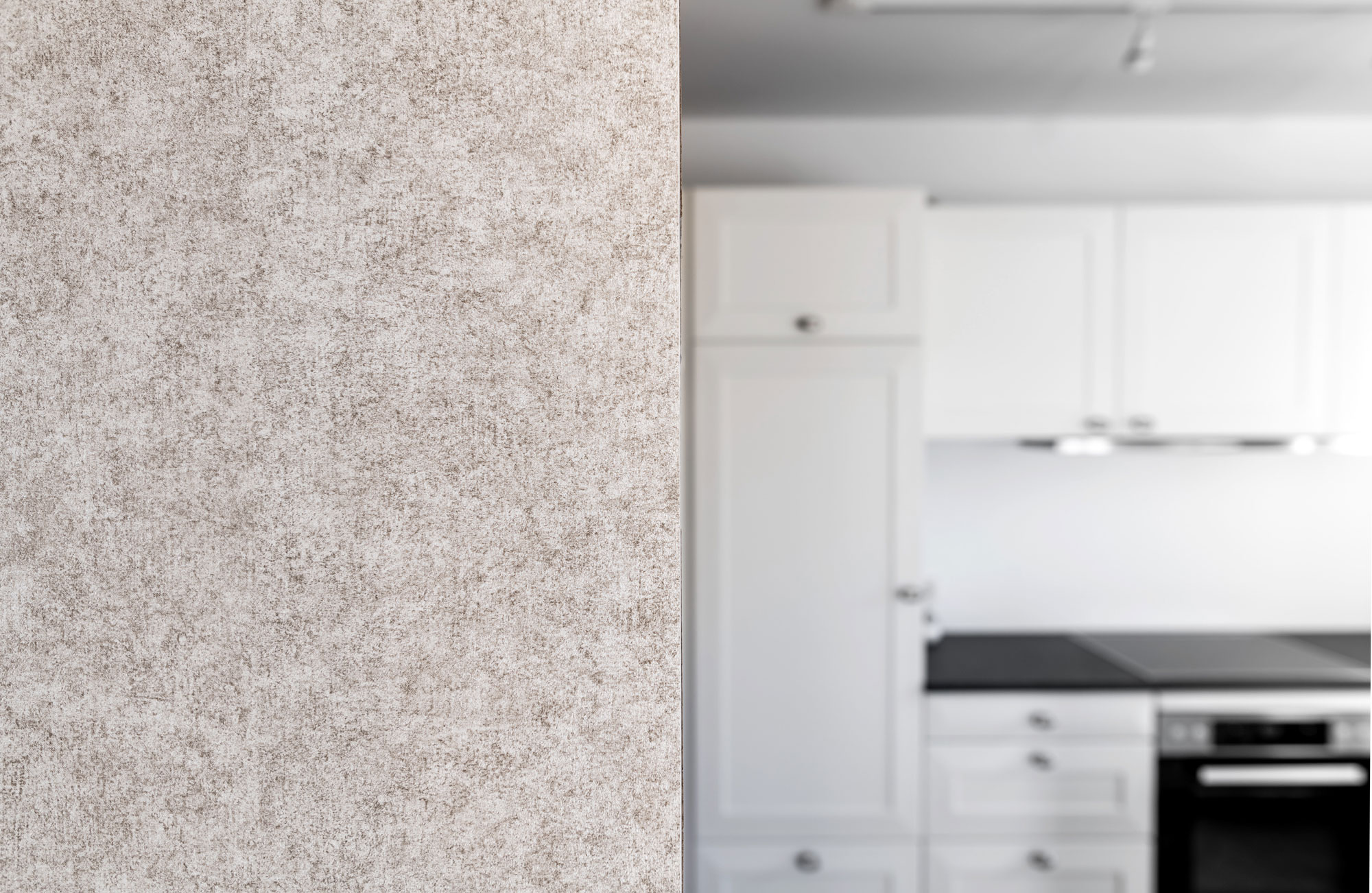 Eine interessante weiß, grau und altrosa gefleckte Tapete an einer Küchenwand.
