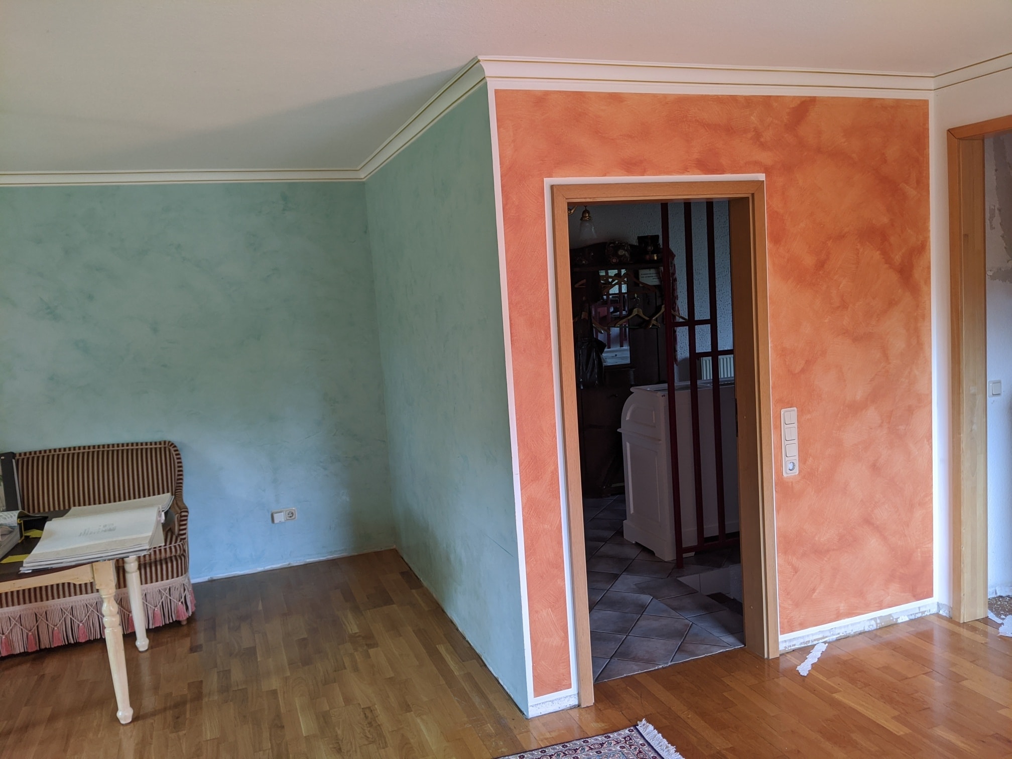 Eine altrosa Wand und eine türkise Wand in einem Zimmer vor den Malerarbeiten. Der Farbkontrast ist furchtbar.