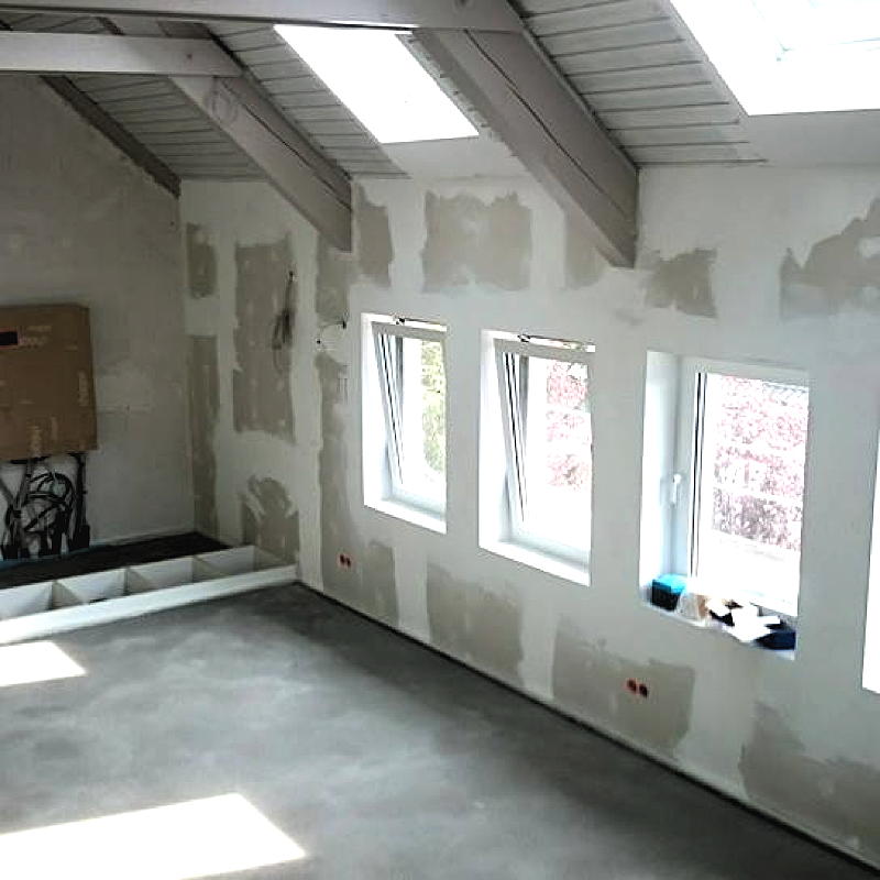 Gespachtelte Rigipsplatten und viele Fenster in einem Dachgeschoss, welches ausgebaut wird.